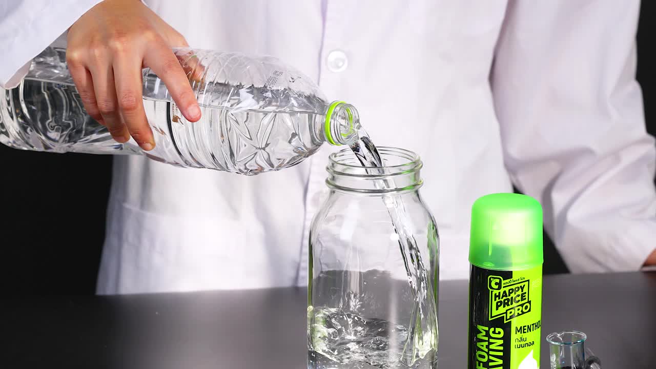 una persona con una bata de laboratorio vierte líquido en un frasco, demostrando un experimento de reacción química