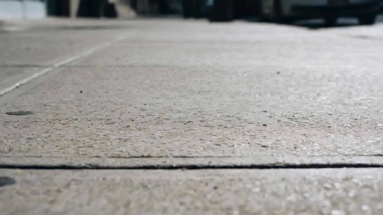 Placing low-angle camera capturing concrete slab on city sidewalk documenting expansion joint, bolt