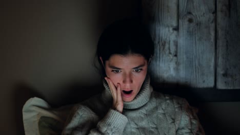 젊은 여성이 노트북의 충격적인 내용에 반응하고 있습니다.