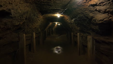 dark underground mine tunnel with lights and wooden supports