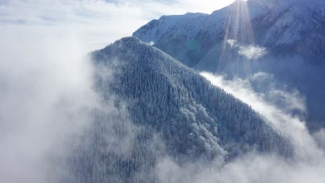 Schneebedeckte-Bucegi-Berge,-Die-Durch-Die-Wolken-Ragen,-Mit-Sonnenstrahlen