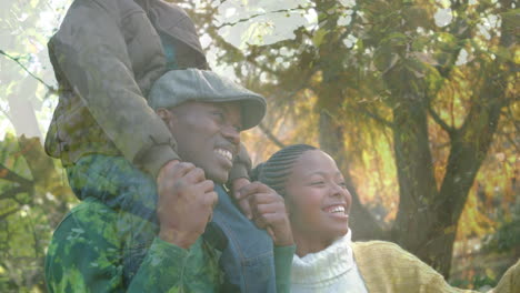 animation of leaves over happy african american couple with child