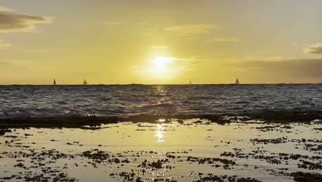 A-breathtaking-view-of-the-sun-setting-over-the-ocean,-casting-a-golden-glow-across-the-water-and-beach