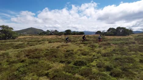 Drone-following-behind-mountain-bike-riders-and-moving-up-alongside-them-on-the-top-of-a-mountain-trail