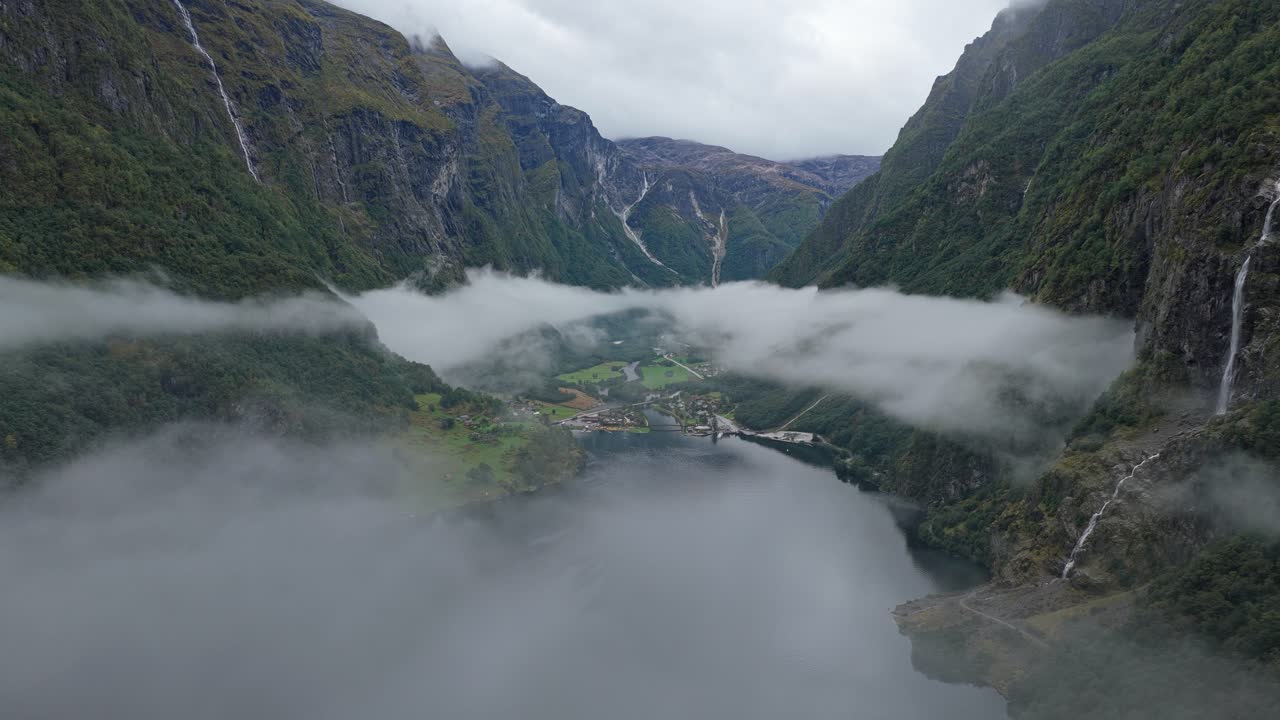 Luftfoto af landsbyen Gudvangen under stejle fjordklipper og skyer