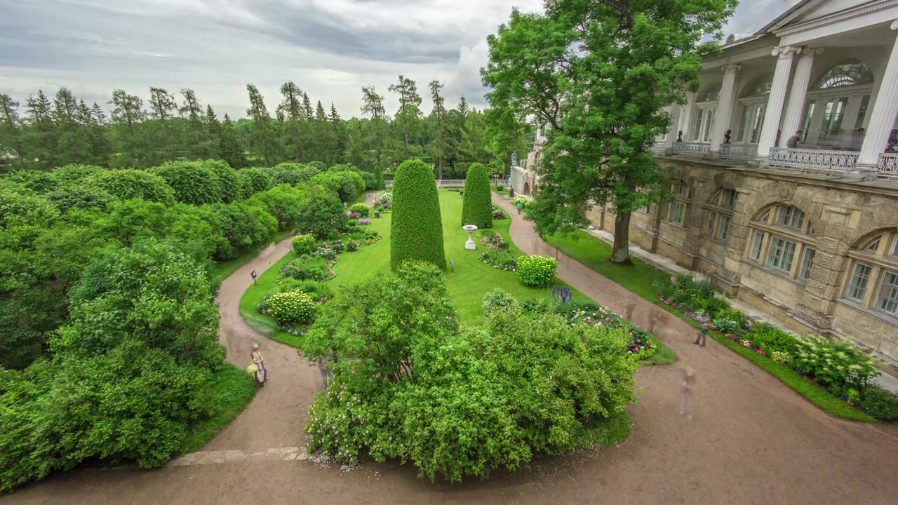 ロシア、サンクトペテルブルクのエカテリーナ公園タイムラプス：アンティークギャラリーと彫刻の近くの庭園。曇りの夏の日に、花の配置、木々、低木で飾られた優雅な庭園を探索