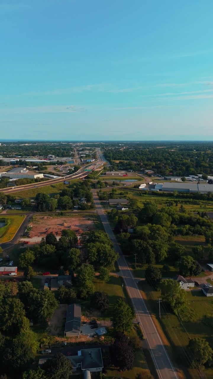 Svincolo trafficato dell'autostrada 41 che si estende oltre un verde quartiere suburbano sotto un cielo estivo sereno, utile come infrastruttura o sobborgo del Midwest in un'inquadratura verticale di ambientazione. Ideale per i social media.