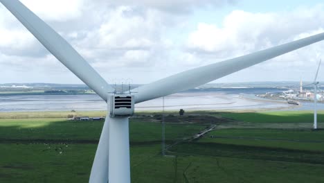 Alternative-green-energy-wind-farm-turbines-spinning-in-Frodsham-Cheshire-fields-aerial-view-closeup-orbit-right