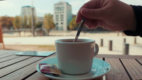 La-Mano-De-Una-Niña-Está-Vertiendo-Azúcar-Y-Bebiendo-Chocolate-Caliente-En-El-Parque,-Montpellier---Francia