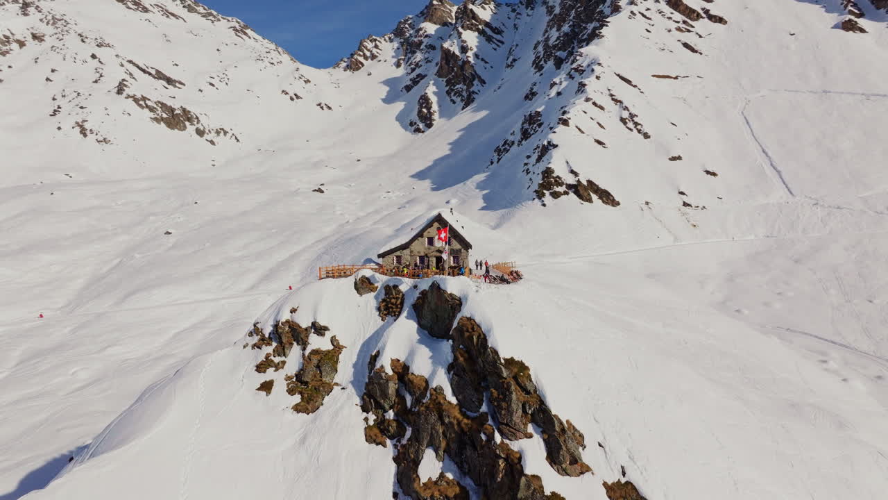 Aerial orbit around Cabane Mont Fort, mountain hut nestled in the Swiss Alps, surrounded by stunning alpine peaks.