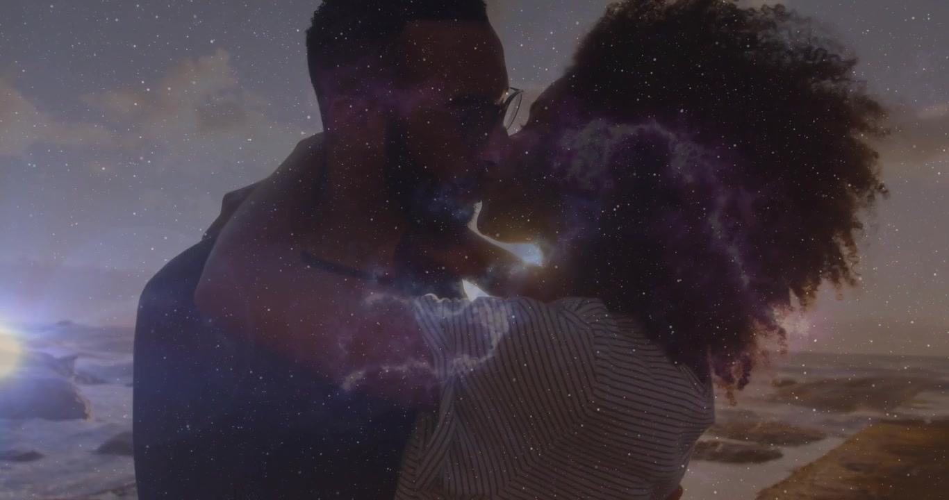 Une superposition cosmique scintillante introduisant une femme étreignant un homme et partageant leur amour sur un film se déroulant sur une plage de sable.