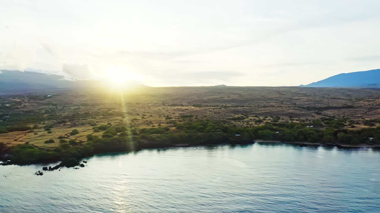 A luz do sol da manhã ilumina a paisagem vulcânica do Havaí, banhando o litoral em um brilho dourado enquanto as ondas calmas do oceano cintilam sob o vasto céu do Pacífico