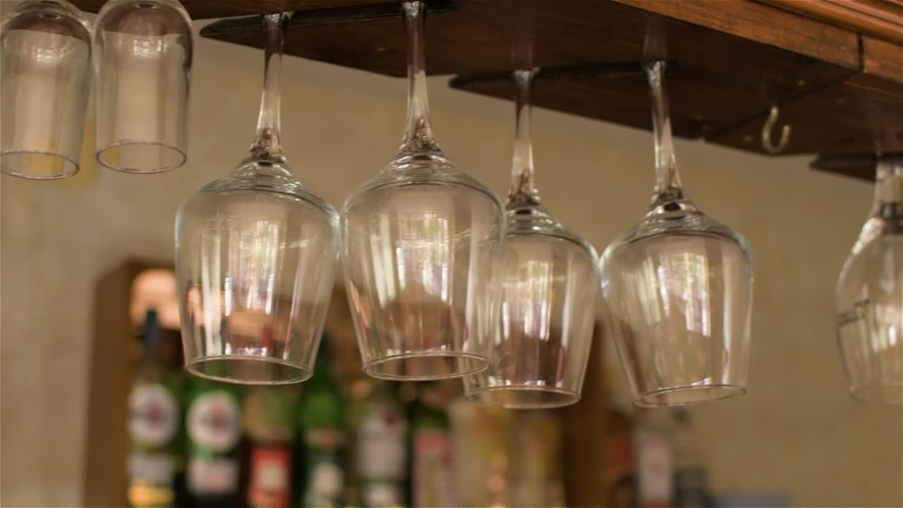 vista de varios vasos de cristal colgados boca abajo en un bar