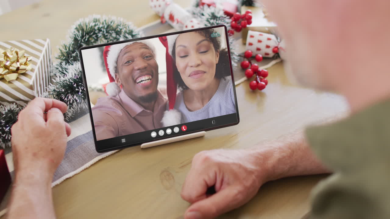 un anciano caucásico tiene una llamada de video de navidad con una pareja afroamericana.