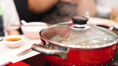 friends gather around steaming hotpot meal