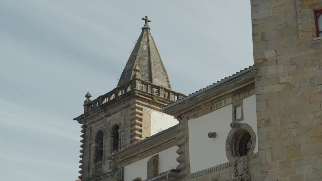 Vista ravvicinata dal basso della storica torre in pietra e della facciata del complesso del Palazzo Revillagigedo sotto un cielo luminoso a Gijon, Asturie, Spagna.