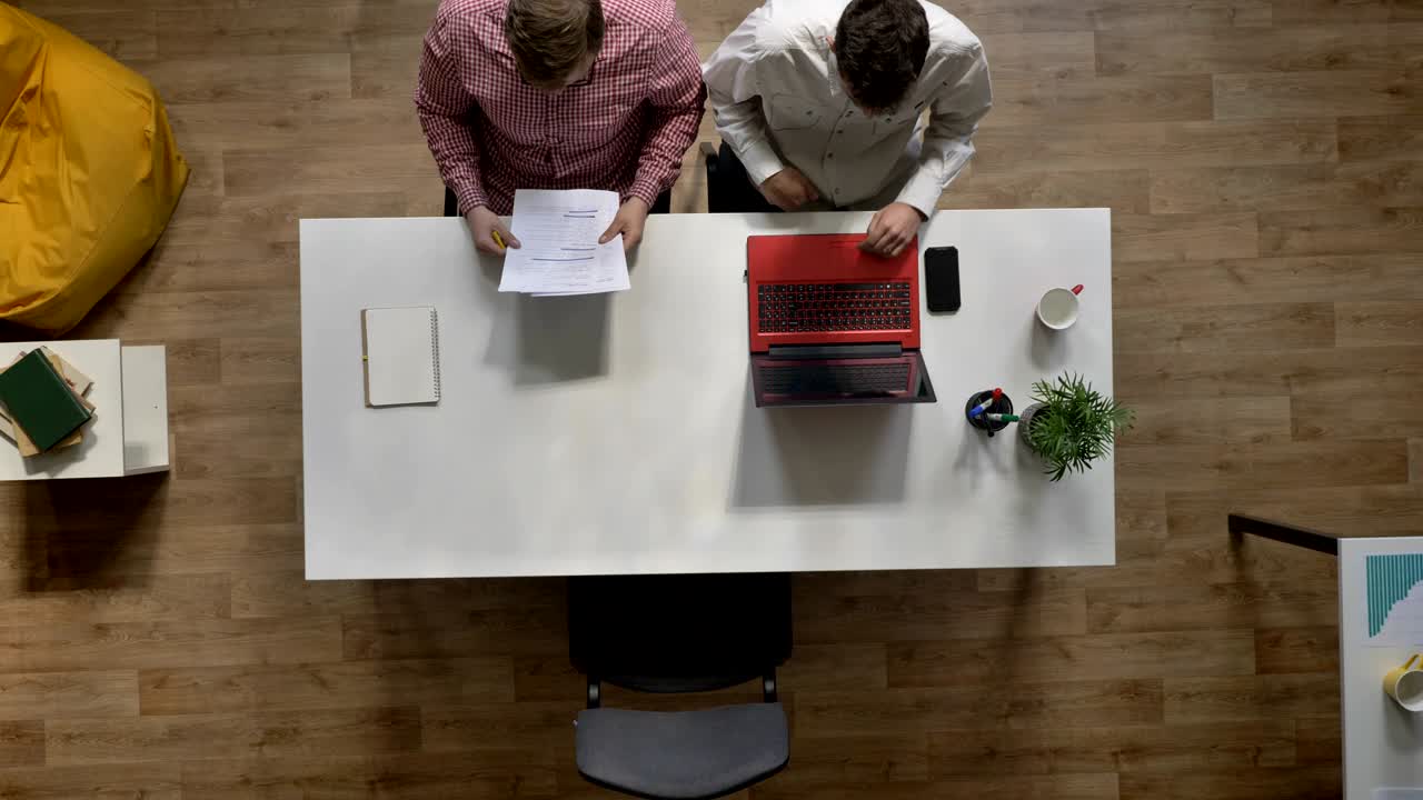 Ung kvindelig kandidat kommer til jobsamtale, giver hånd til arbejdsgivere, sidder på et moderne kontor, set fra oven.