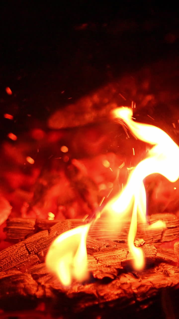 Red flaming on a firewood. Burning logs close up view. Vertical video