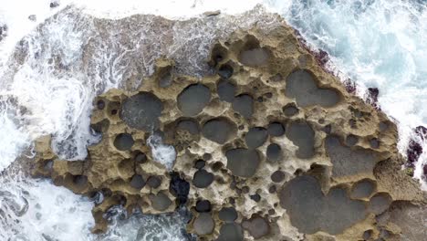 volcanic built coastline of nusa penida island near broken beach hit by strong waves, aerial top view shot