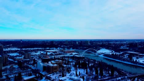 Retención-Aérea-De-Invierno-Sobre-La-Propiedad-De-La-Legislatura-De-Edmonton-Cubierta-De-Nieve-En-Proceso-De-Renovación-Junto-A-La-Junta-De-Finanzas-Del-Tesoro-De-Alberta-Con-Mini-Icebergs-Derretidos-Río-Abajo-Por-El-Puente-Moderno-Walter-Dale