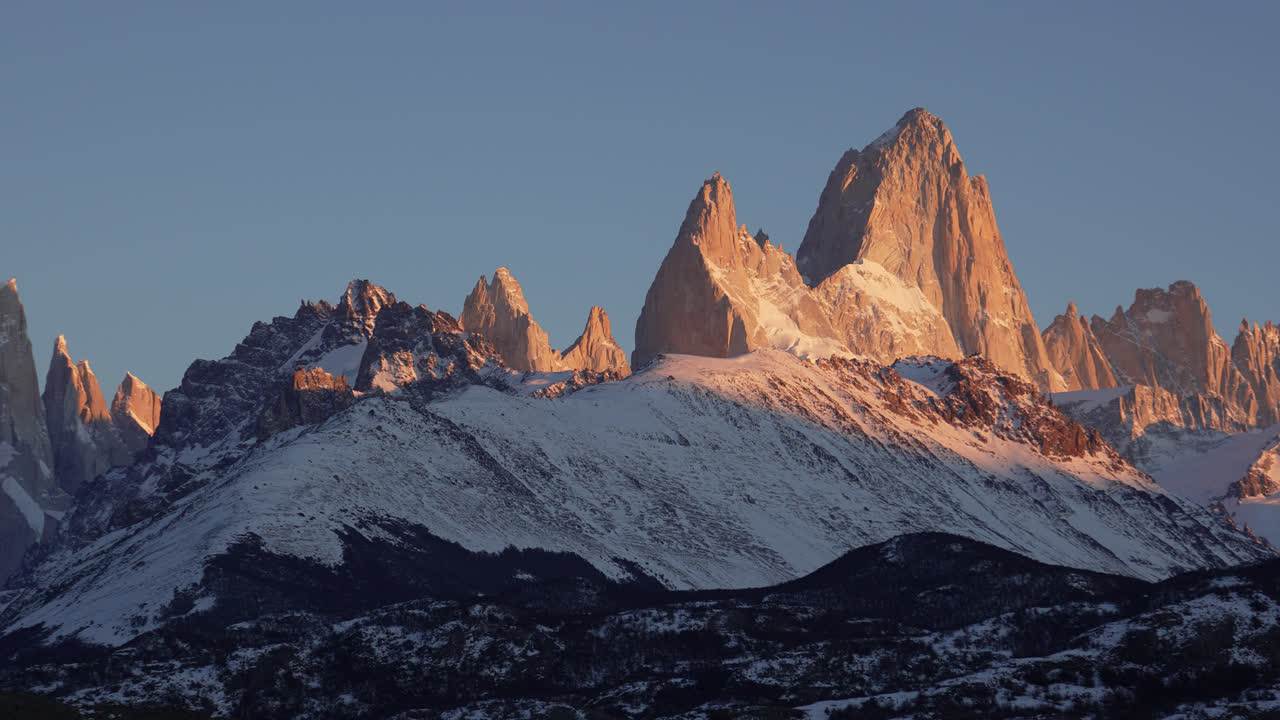 Le cime aspre dei monti Fitz Roy e Torre bagnate dalla luce soffusa dell'alba, ripresa panoramica