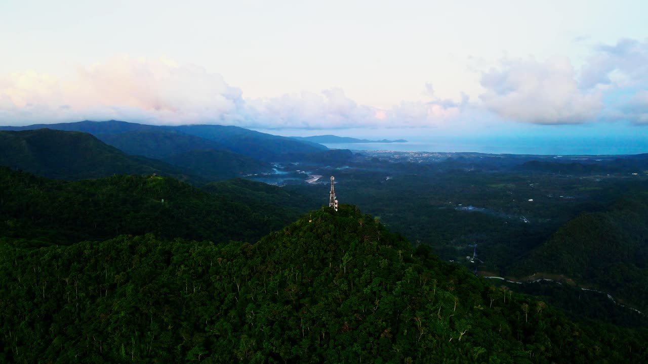 Panoramic view of Mount Cagmasuso peak and satellite tower overlooking tropical island Catanduanes, Philippines during sunset - aerial orbit
