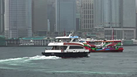 a stationary footage of a crossing shipping vessel and the star ferry cruising along the waters of victoria harbour in hong kong