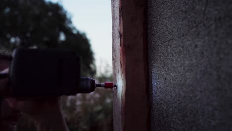 A-Man-is-Drilling-Nail-into-Wood-to-be-Used-for-Building-a-Greenhouse-in-Indre-Fosen,-Norway---Close-Up