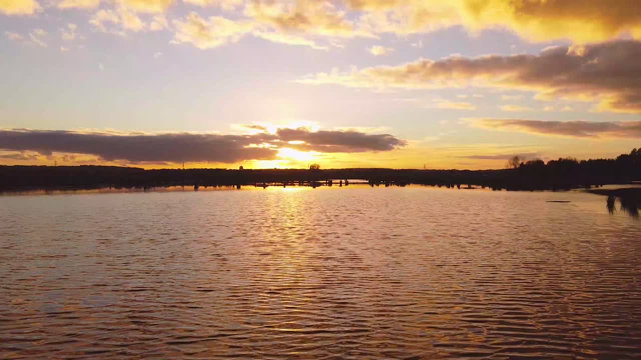 Areal drone shot of flooded agriculture crops fields with a perfect reflection at sunset. Flying at a low altitude over the water from the sunset.