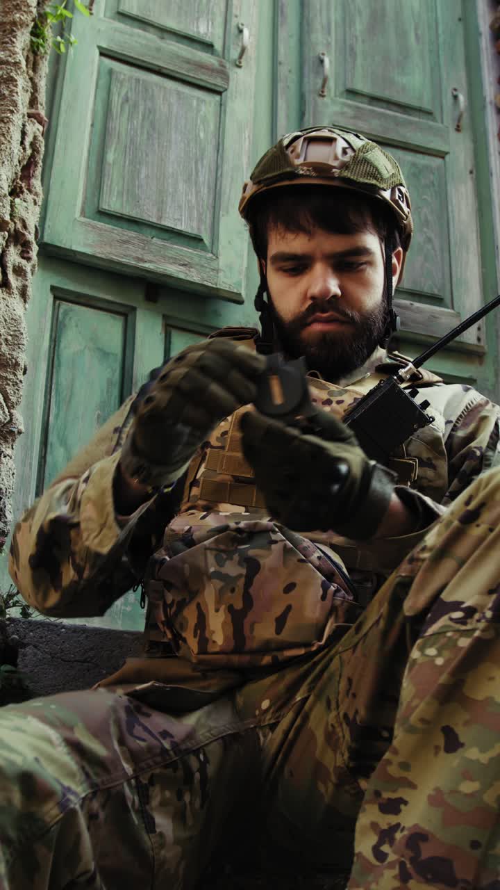 Soldier Sitting Near A Destroyed House Checks His Compass