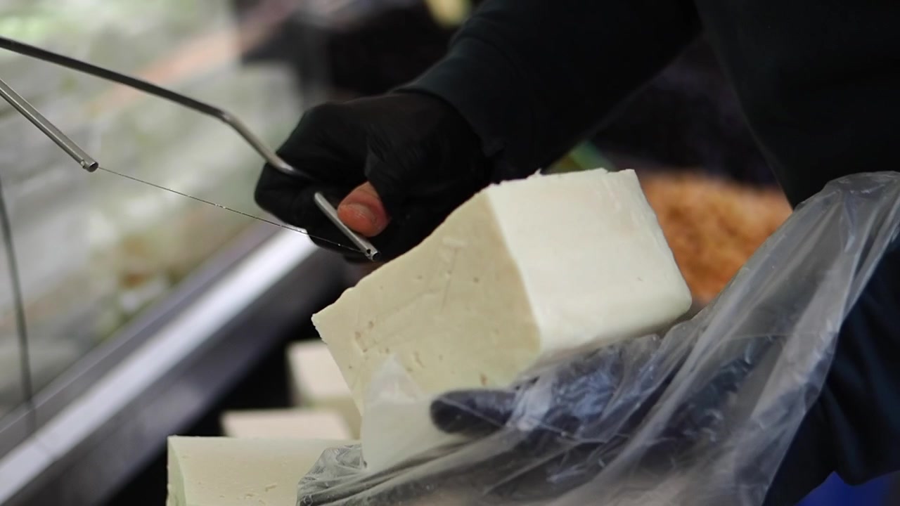 Close-up of Hand Cutting White Cheese Block with a Wire Cutter