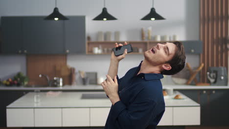 Attractive-man-dancing-with-mobile-phone-in-hand.-Cheerful-guy-smiling-to-camera