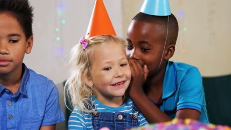 Boy-whispering-to-girl-while-sitting-with-friends-during-birthday-party-4k