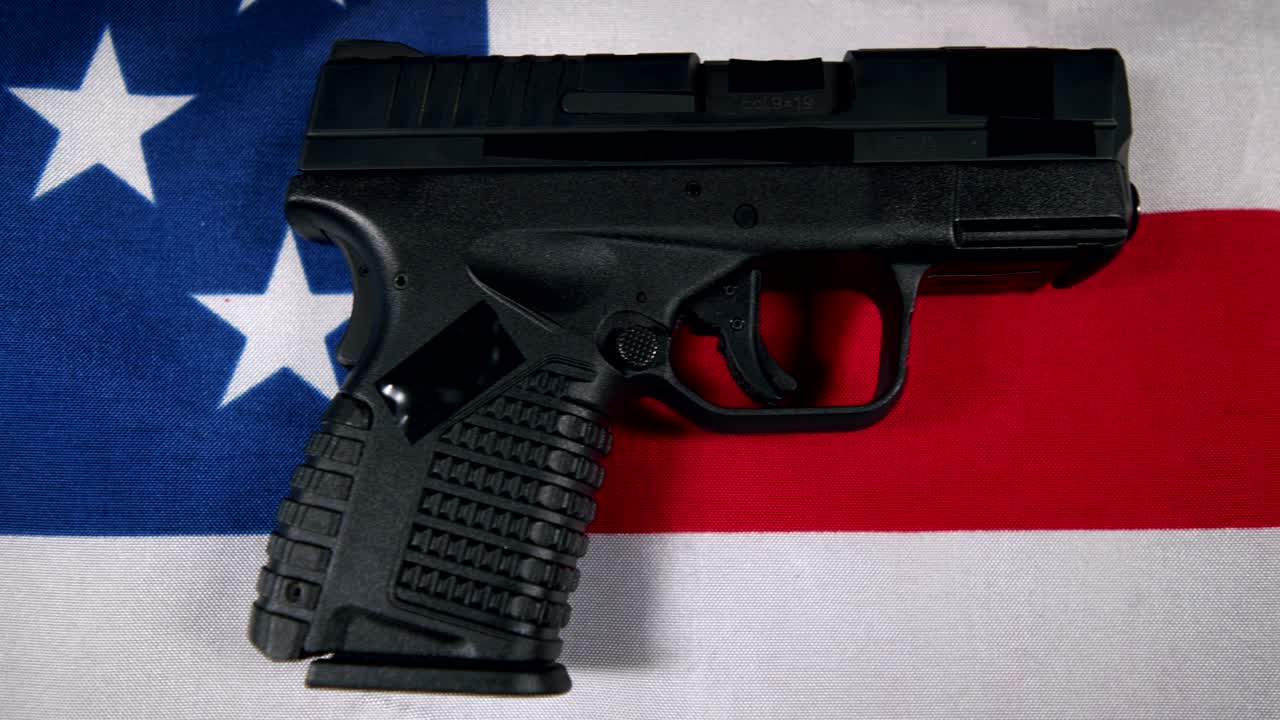black Semi-Automatic 9mm Handgun on American flag,  right hand side view, slow pan right to left, 4k