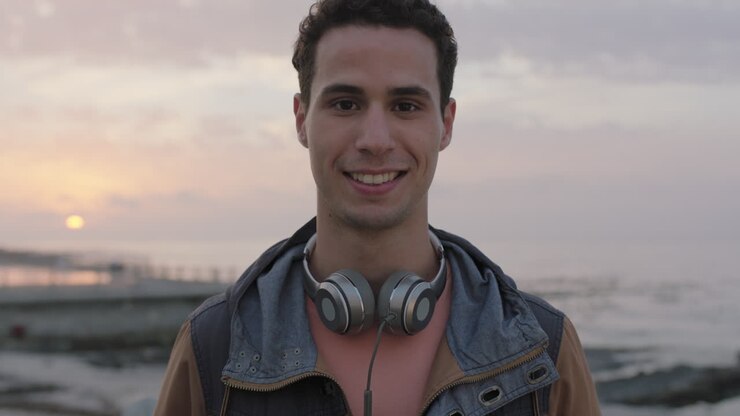ritratto di un giovane attraente che sorride guardando la telecamera sullo sfondo di un bellissimo tramonto