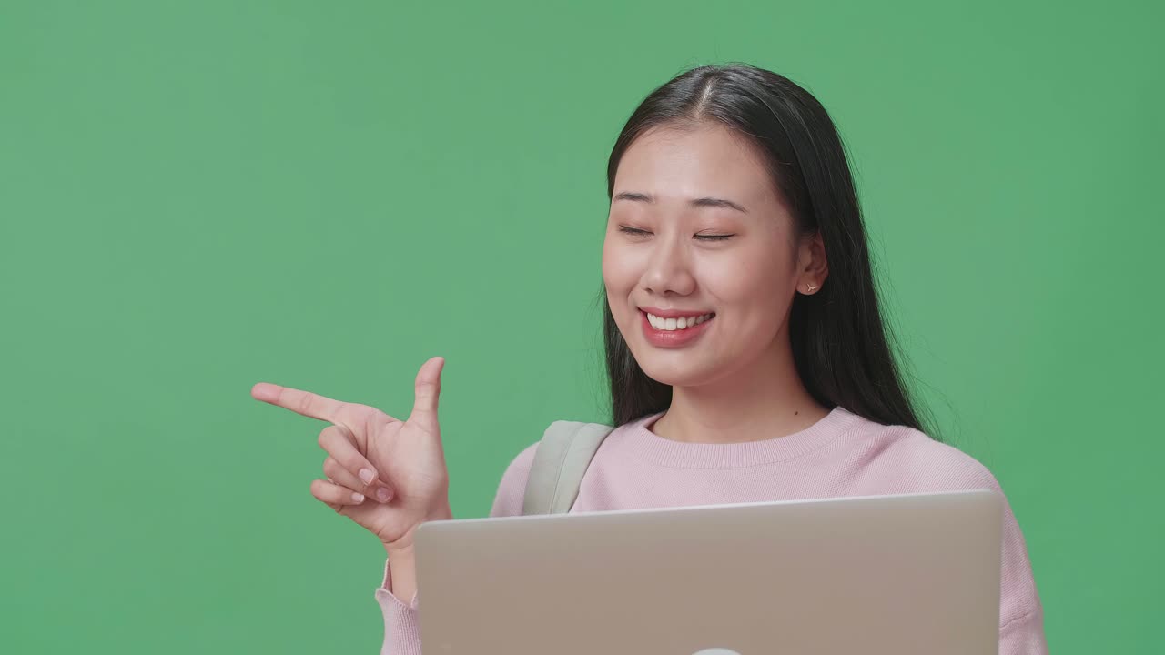 estudiante asiática usando una computadora portátil y dedos directos lado en el estudio de pantalla verde
