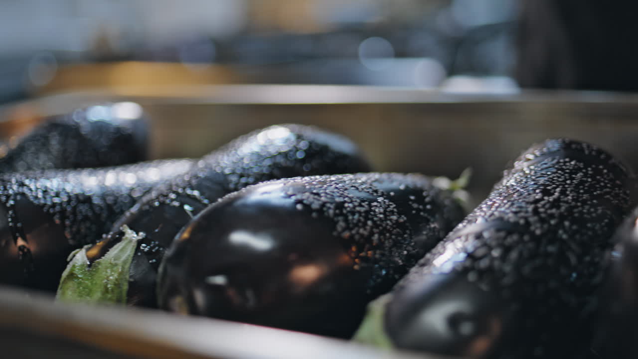 Chef seasoning fresh eggplants in modern kitchen closeup. Unknown cook salting