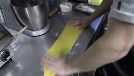 pasta being floured and brushed off by a chef on a kitchen counter