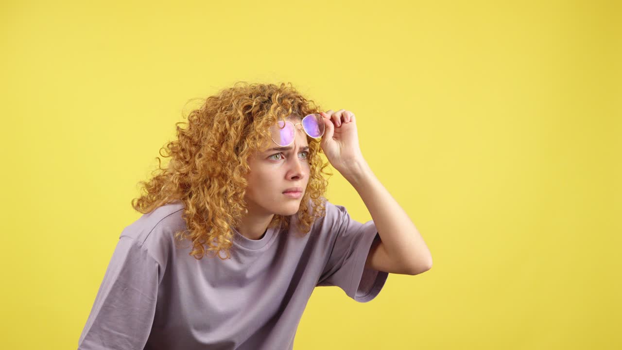 Young Woman with Curly Hair and Glasses Looking Intently