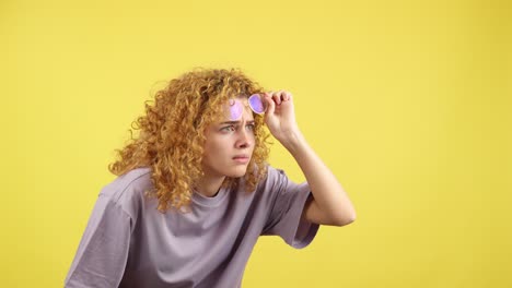 young woman with curly hair and glasses looking intently