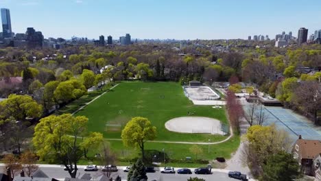 Drone-flying-away-from-a-park-with-a-baseball-diamond-on-a-spring-day-in-Toronto