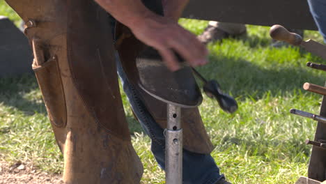 a farrier shoeing a dark brown horse at an equestrian competition