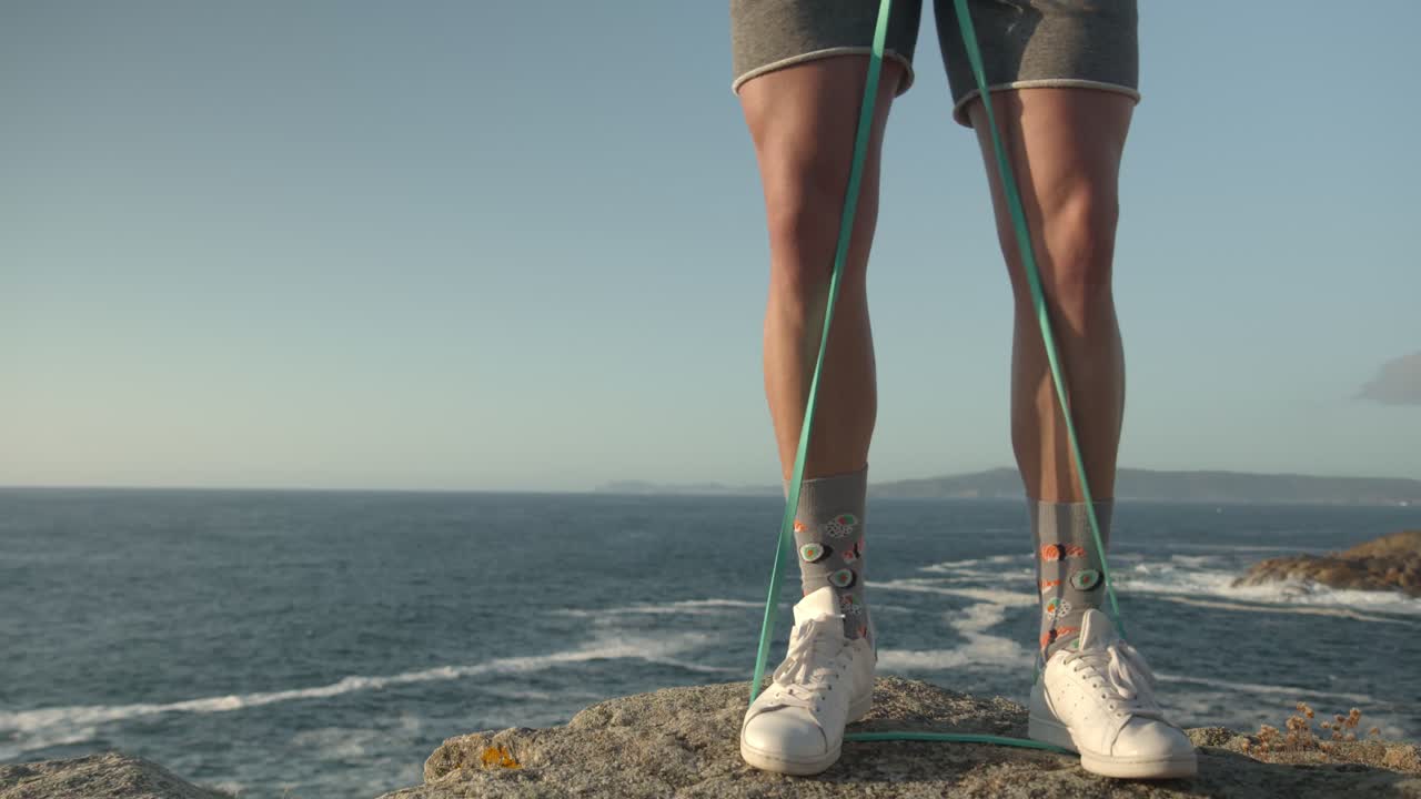 발을 가진 탄력 밴드로 훈련하는 익명의 운동 선수