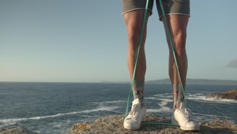 anonymous athletic man training with elastic band with the foots