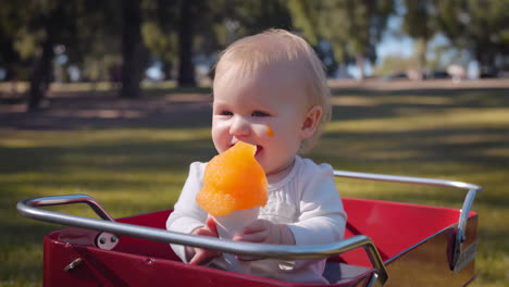 baby eating a snow cone in a wagon