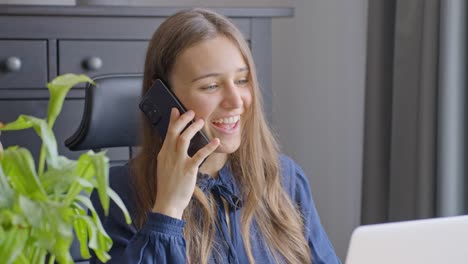 joven mujer de negocios recibiendo buenas noticias mientras habla por teléfono en la oficina