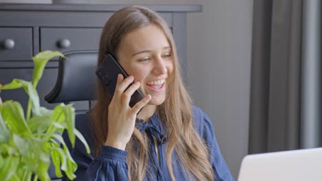 young businesswoman getting good news while talking on phone in office