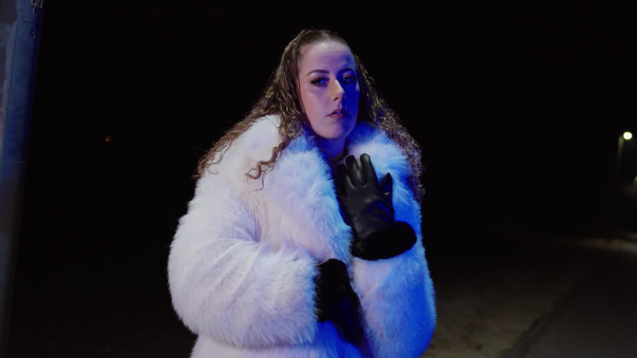 Scena notturna cinematografica di una donna sola in una strada tranquilla, che si abbottona il cappotto e lo stringe per scaldarsi, con un'aria triste e abbandonata. Concept per solitudine, rottura, freddo invernale, emotività