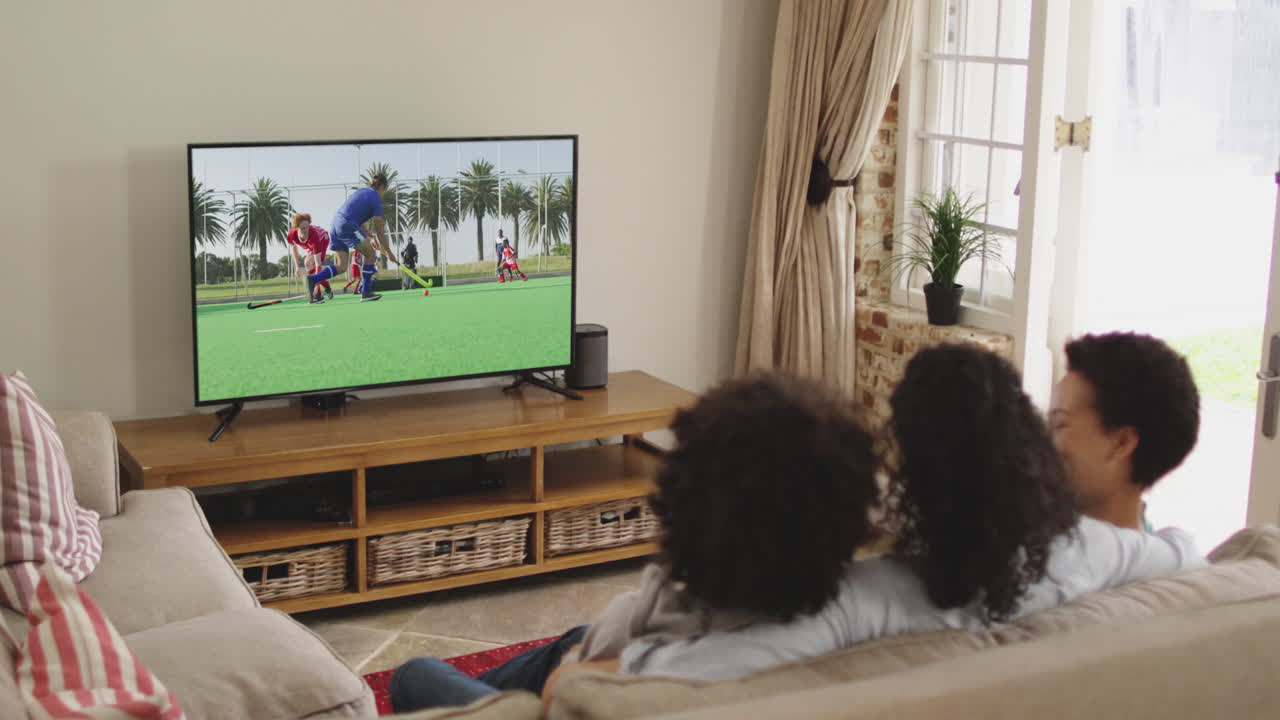 Famiglia felice seduta a casa insieme che guarda una partita di hockey in TV