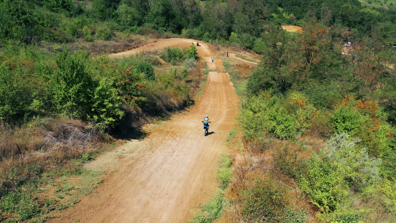 Vista aerea da drone di un motociclista durante una gara di motocross, pista fangosa, moto da rally, vegetazione circostante. Movimento al rallentatore
